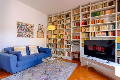 a living room with a blue couch and book shelves at Elegantis Monti Penthouse With Private Terrace and Colosseum View in Rome