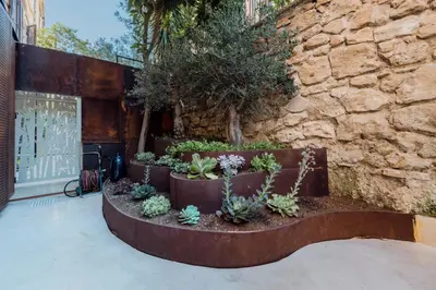 a garden with succulents and plants in front of a stone wall at Skylife Garden of Olives in Rome