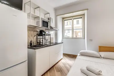 a kitchen with white cabinets and a bed in a room at Albadoro Apartment in Rome