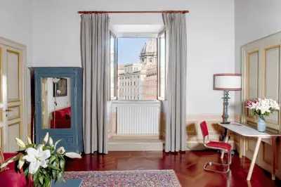 a living room with a large window and a red chair at Caesarina Roma, Luxury apartment in Rome