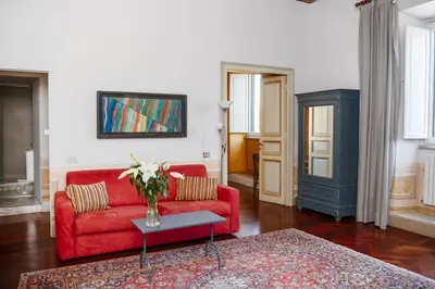 a living room with a red couch and a vase of flowers at Caesarina Roma, Luxury apartment in Rome