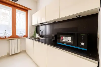 a kitchen with white cabinets and a black microwave at Casa Chanel in Rome