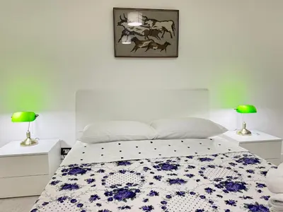 a white bedroom with a bed with a floral bedspread at Always Home in Rome