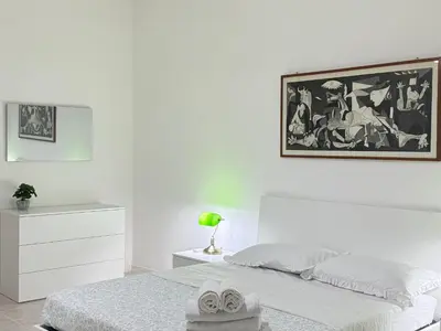 a white bedroom with a bed and a painting on the wall at Always Home in Rome