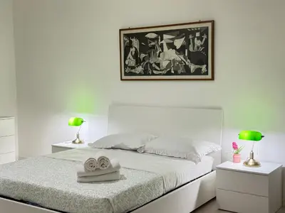 a bedroom with a white bed with two lamps and a picture at Always Home in Rome