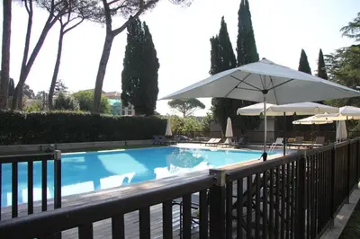 a swimming pool with an umbrella and chairs and umbrellas at Clio Apartment in Rome