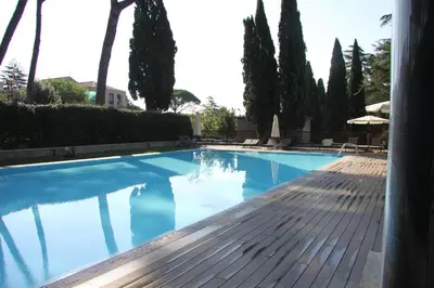 a large blue swimming pool with trees in the background at Clio Apartment in Rome