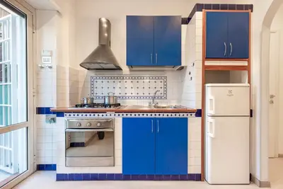 a kitchen with blue cabinets and a refrigerator at Vatican Museums Apartment with Romantic Terrace in Rome