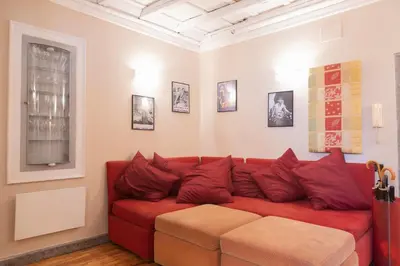 a red couch in a living room with pictures on the wall at La Dolce Vita Pantheon Suite in Rome