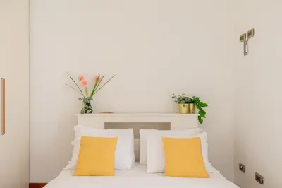 a bedroom with white walls and yellow pillows at iFlat Vintage Retreat - Comfort in Central Rome in Rome