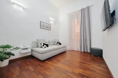 a living room with a white couch and a wooden floor at Maison Florienne in Rome