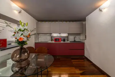 a kitchen with a glass table with a vase of flowers at Lungaretta Trastevere Penthouse Mimì & Cocò Home in Rome