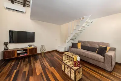 a living room with a couch and a tv at Lungaretta Trastevere Penthouse Mimì & Cocò Home in Rome