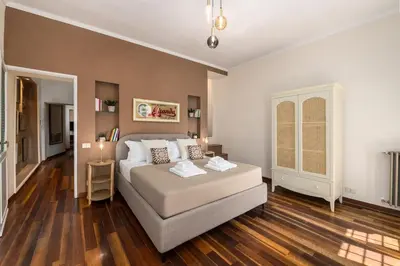 a bedroom with a bed in a room with wooden floors at Lungaretta Trastevere Penthouse Mimì & Cocò Home in Rome