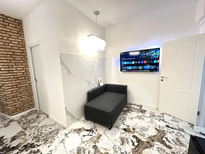 a room with a black chair and a tv on the wall at Callas Luxury Apartment in Rome