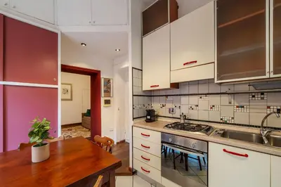 a kitchen with white cabinets and a wooden table at Casa Mia Trastevere in Rome