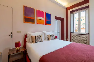 a bedroom with a white bed with paintings on the wall at Casa Mia Trastevere in Rome