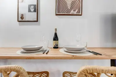 a table with two white plates and a bottle of wine at Colosseum Loft, Rustic-modern charm in Rome