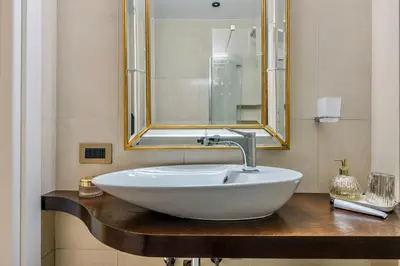 a bathroom with a white sink and a mirror at Colosseum 1 Min Design Apt with Private Courtyard in Rome