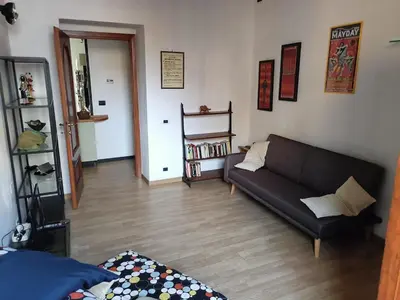 a living room with a black couch and a wooden floor at GattaGuest in Rome