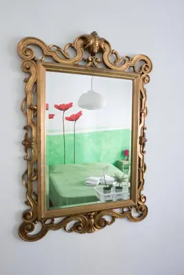 a mirror on a wall with a table and flowers at Next Stop Roma Affittacamere Casilino in Rome