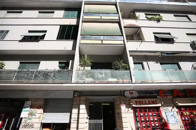 a tall white building with a store in front of it at Next Stop Roma Affittacamere Casilino in Rome