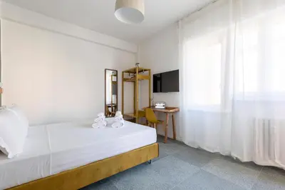 a white bedroom with a bed and a desk at Hostly-San Paolo Charme Apartment in Rome