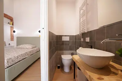 a bathroom with a sink and a toilet and a bed at Castle Suite Borgo in Rome