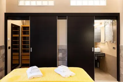 a bathroom with black sliding doors and towels on a bed at Andy Home in Rome