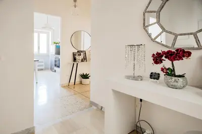 a white room with a mirror and a vase with red flowers at Geppy Vacation home near Saint Peter Basilica in Rome