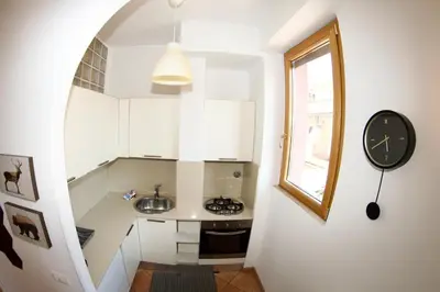 a kitchen with white cabinets and a clock on a wall at San Vito Cozy Apartment in Rome