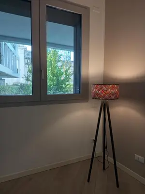 a lamp on a tripod in a room with two windows at La Casa di Lella in Rome