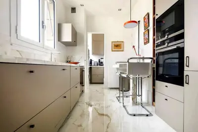 a kitchen with white cabinets and a bar stool at Appartamento Marissia in Rome