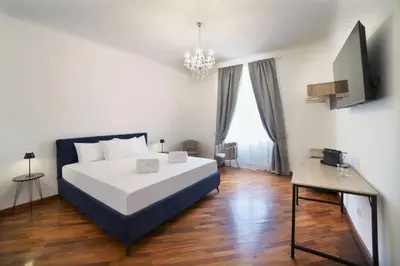 a bedroom with a large white bed and a chandelier at DolceVite - Fontana Di Trevi in Rome