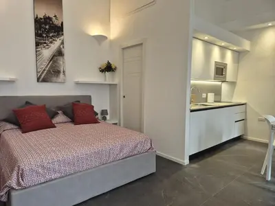 a bedroom with a bed with red pillows and a kitchen at Domus Tirso Mini Loft with independent entrance in Rome