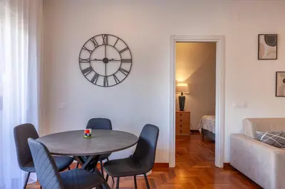 a dining room with a table and chairs and a clock at Vatican Hills Apartment in Rome