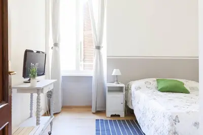 a white bedroom with a bed and a window at Domus Merulana Bed and Breakfast in Rome