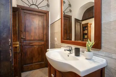 a bathroom with a sink and a wooden door at Santa Caterina by the Pantheon - 2BR in Rome