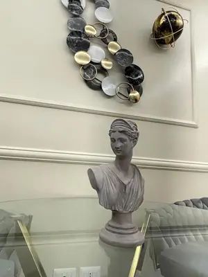 a glass table with a bust on a wall with a clock at The Madame Sofia - A Secret Hotel - Small Boutique Hotel & Apartments in Rome