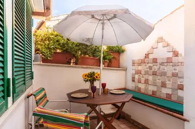 a table and chairs with an umbrella on a balcony at Trastevere Enchanting Apartment in Rome