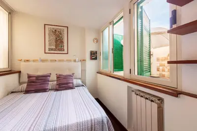 a bedroom with a bed and two windows at Trastevere Enchanting Apartment in Rome
