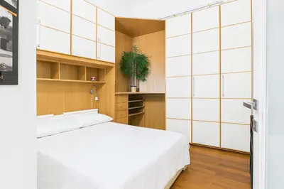 a bedroom with a white bed and wooden cabinets at Esquilino Refined Holiday Home in the Heart of Rome in Rome