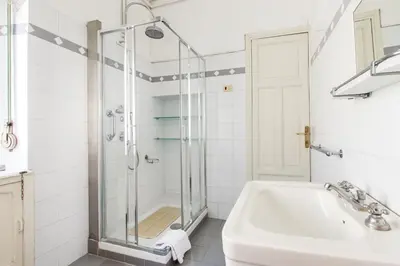 a white bathroom with a shower and a sink at Trastevere Decò Apartment in Rome