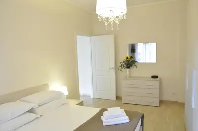 a white bedroom with a bed and a table with towels at Casa Tony in Rome