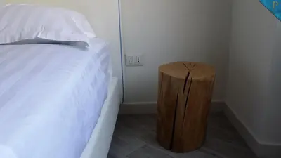 a bedroom with a bed and a wooden stool next to a bedskirts at Piccolotel in Rome