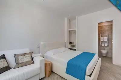 a white bedroom with a bed and a couch at Piccolotel in Rome