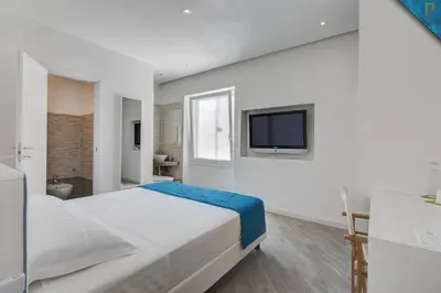 a white bedroom with a large bed and a television at Piccolotel in Rome