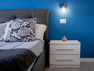 a blue bedroom with a bed and a night stand at Saint Peter Welcoming Apartment in Rome