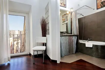 a bathroom with a tub and a chair and a window at Clementina in Rome