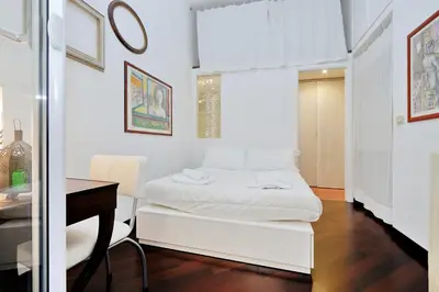 a white bedroom with a bed and a desk at Clementina in Rome